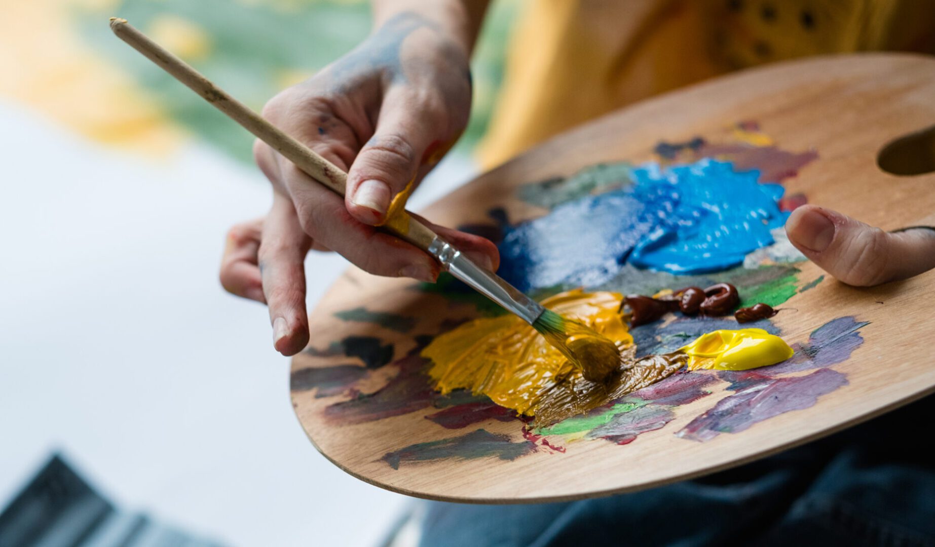 Artist mixing paint on a wooden palette.