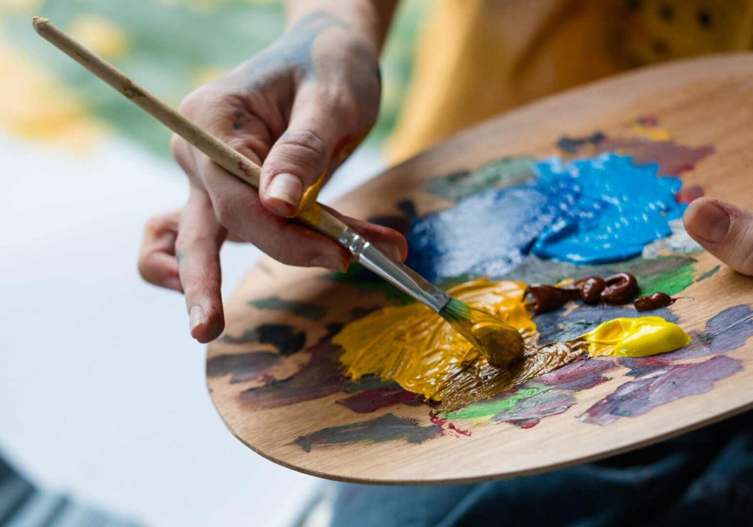Artist mixing paint on a wooden palette.